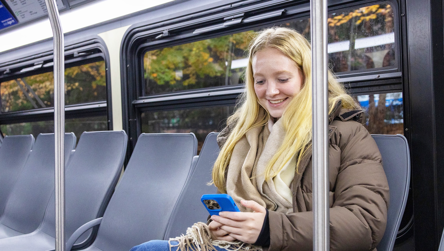 Passenger riding bus while looking down at phone