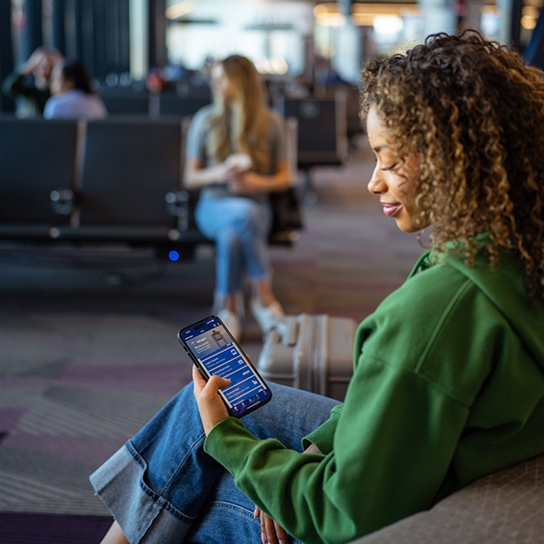 Women holding phone with screen showing the FlyLogan app