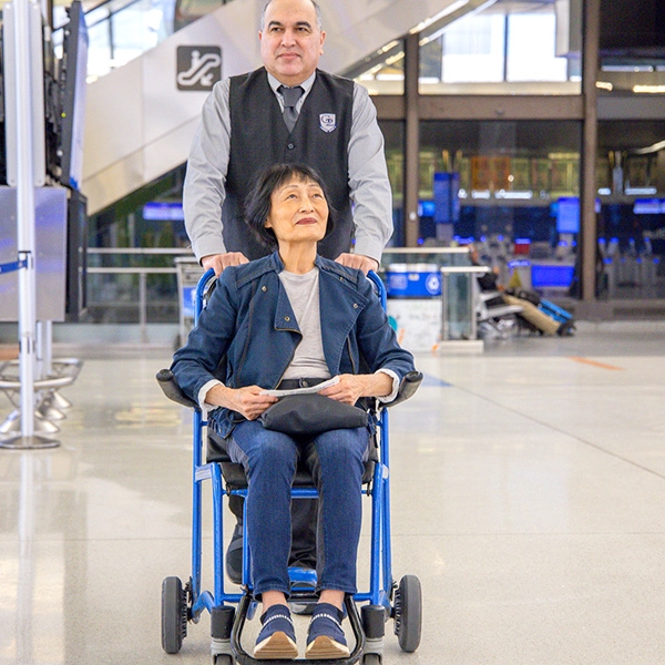 man pushing women in a wheelchair through terminal 