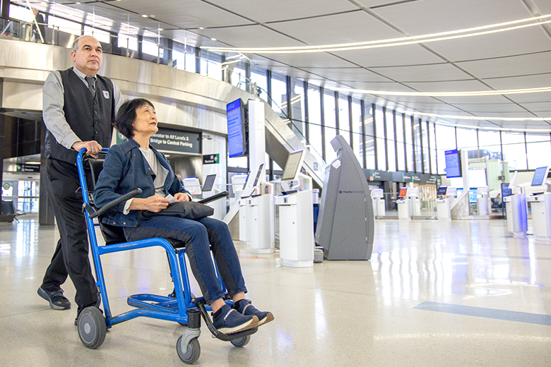 man pushing women in a wheelchair through terminal 